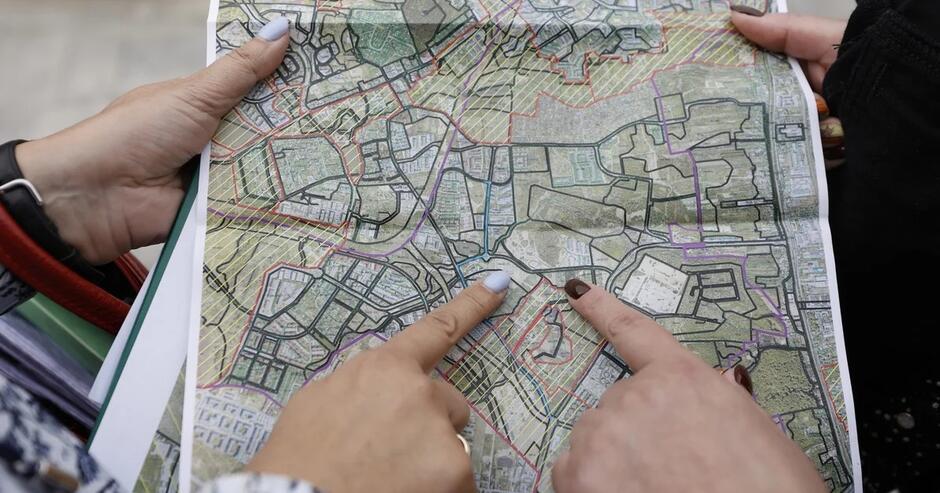 Mapa miasta, dwie kobiece dłonie wskazują palcem jedno miejsce na mapie