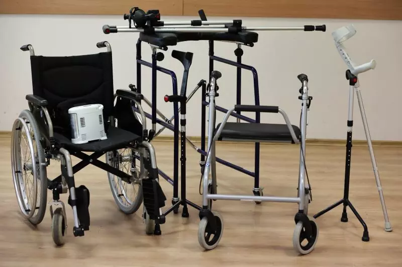 sprzęt rehabilitacyjny, taki jak kule, balkoniki, wózek inwalidzki ustawione w pomieszczeniu