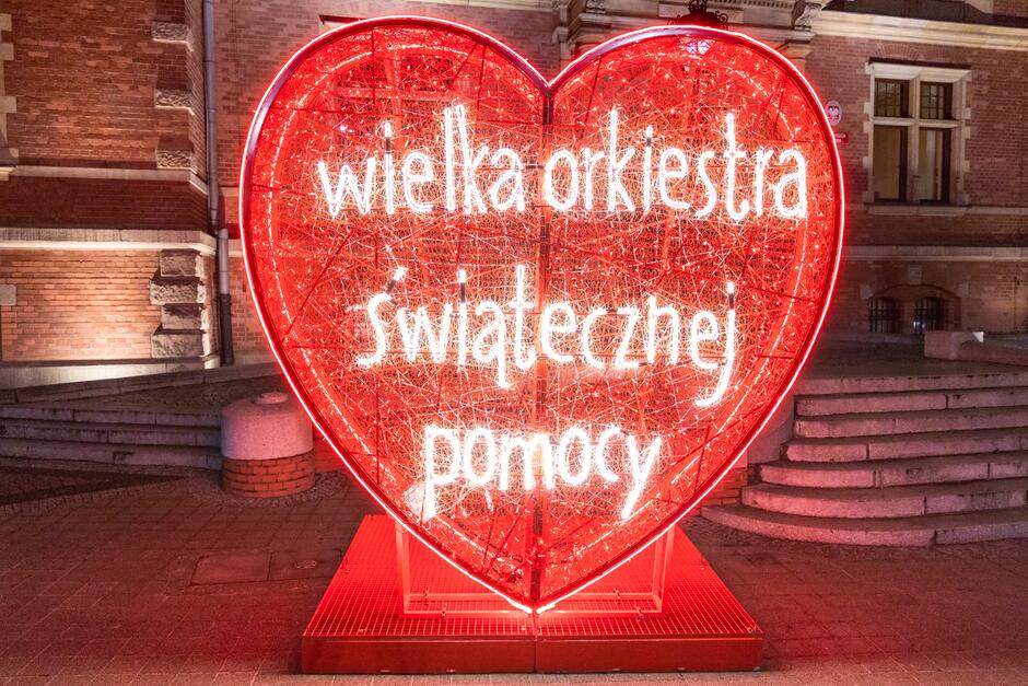 na zdjęciu duże czerwone serce, to iluminacja ogromna która jest przestrzenną rzeźbą, na sercu biały napis wielka orkiestra świątecznej pomocy