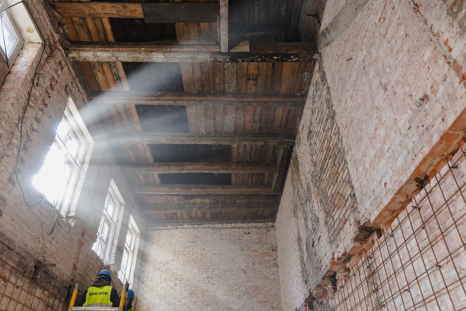 wnętrze rozebranego wewnątrz budynku, widać jedynie ceglane ściany i częściowo drewniane poddasze