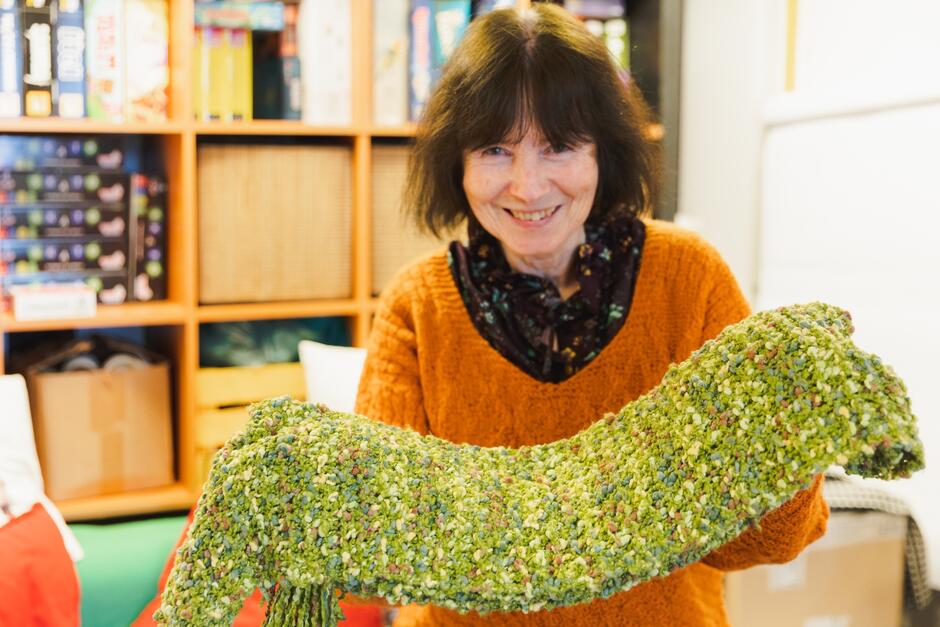 seniorka pokazuje zielony, ręcznie robiony szalik