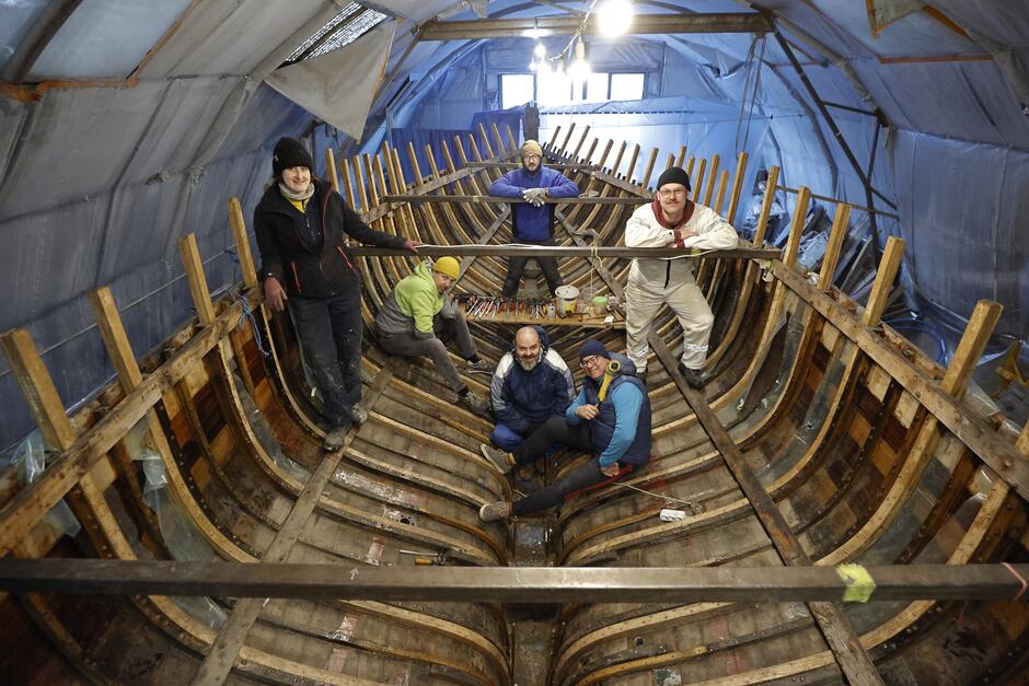 Sześć osób wewnątrz kadłuba remontowanego jachtu