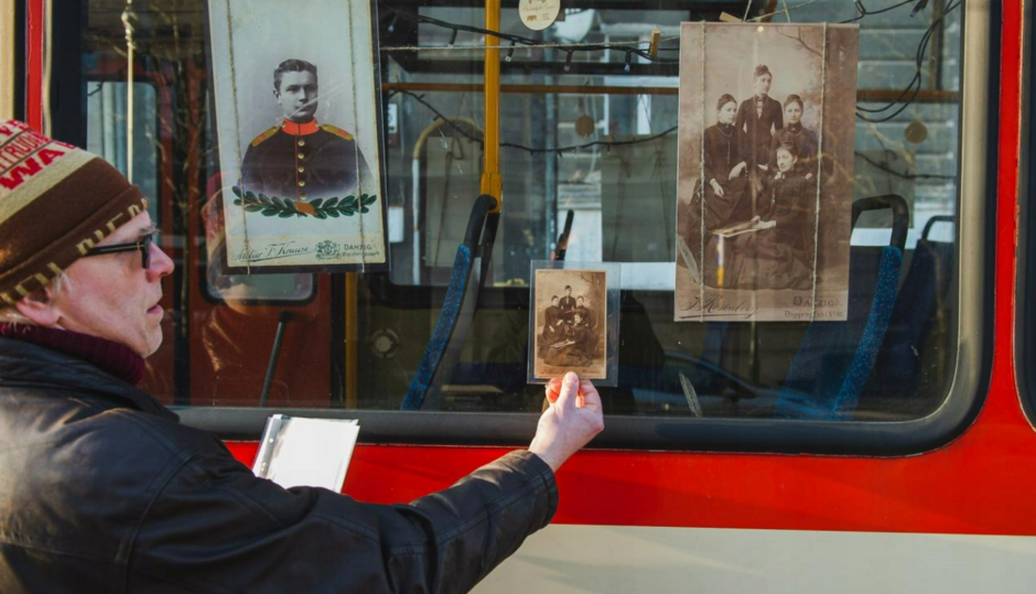 mężczyzna przykłada archiwalne zdjęcie do szyby tramwaju