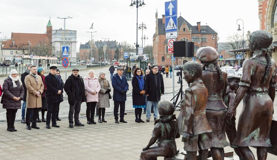grupa ludzi stoi na przeciwko pomnika