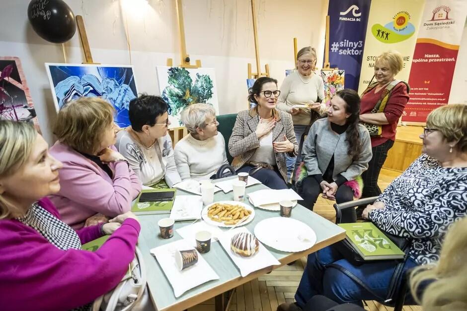 Prezydent Aleksandra Dulkiewicz odwiedziła we wtorek uczestników zajęć Domu Sąsiedzkiego Zakopianka . Na zdjęciu rozmawia przy stole z kilkoma uczestniczkami i animatorami klubu sąsiedzkiego. 