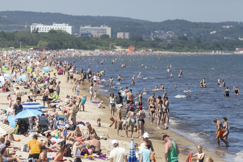 na zdjęciu plaża wypełniona półnagimi plażowiczami, oraz wody zatoki gdańskiej