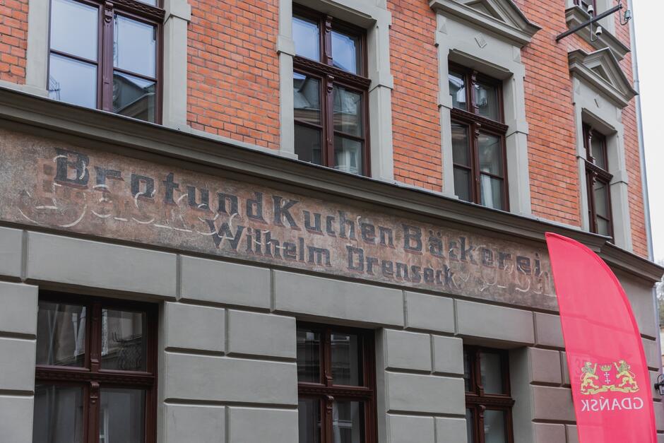 na zdjęciu fragment odnowionej elewacji widać napisy w języku niemieckim, zdobione