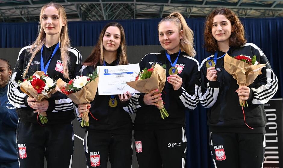 Cztery młode kobiety w dresach z kwiatami w dłoni i medalami na szyi