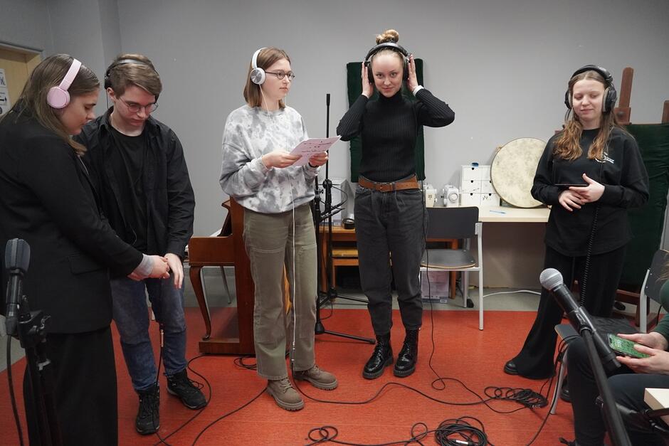 cztery nastolatki i jeden nastolatek w słuchawkach na uszach, w studio nagrań