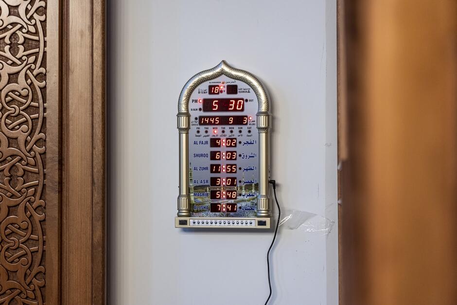 na zdjęciu elektroniczna tablica wyświetlająca między innymi godziny modlitw w meczecie