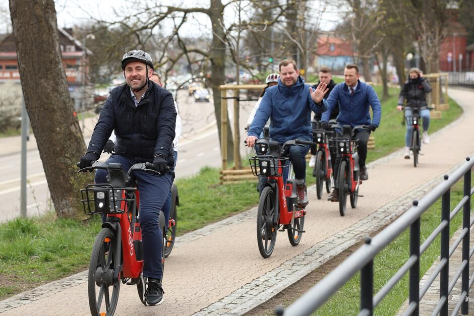 Grupa osób jadących na rowerach w stronę osoby oglądającej fotografię