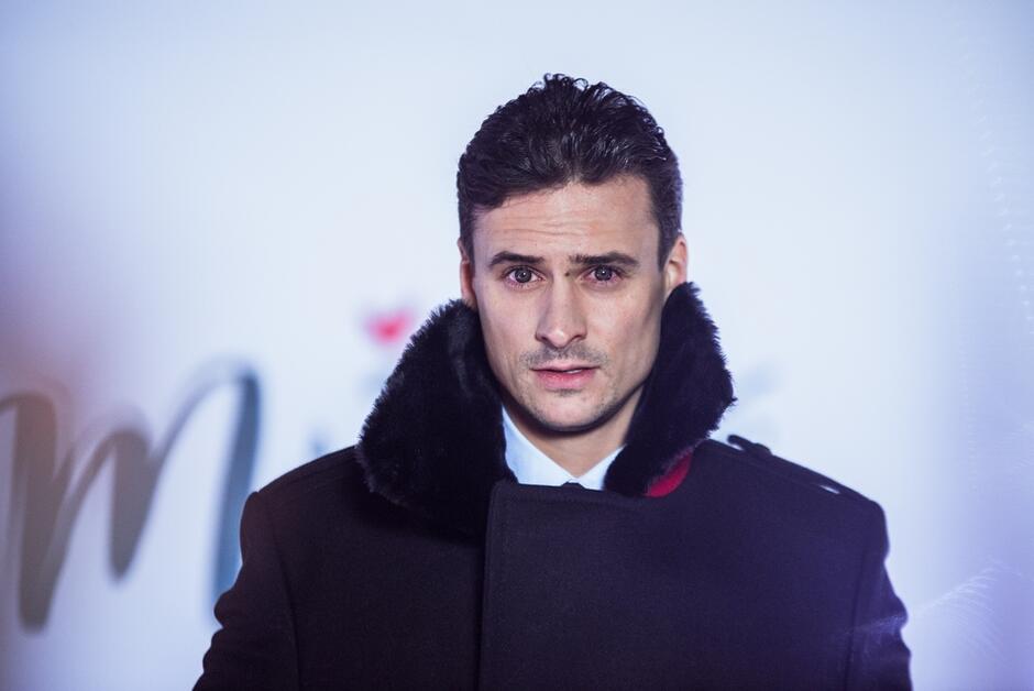 przystojny mężczyzna w płaszczu patrzy w obiektyw