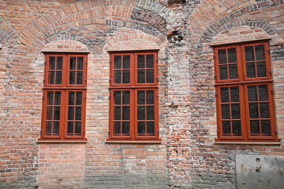 Trzy drewniane okna na ceglanej ścianie. 