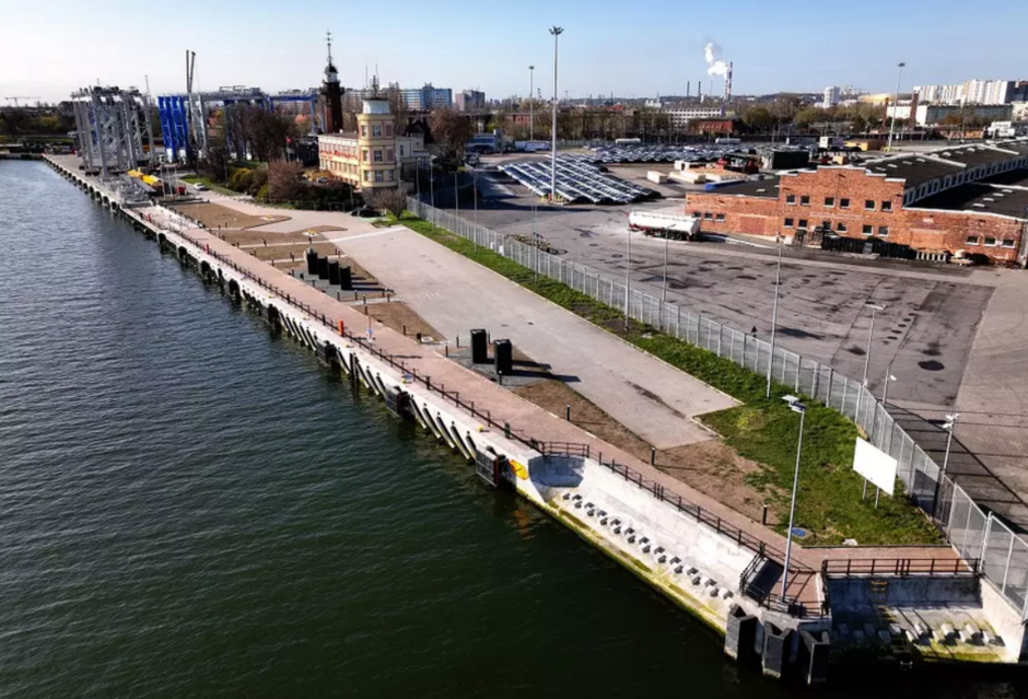 zdjęcie z drona, widać nabrzeże portowe, fragment wód zatoki gdańskiej, w tle budynki portowe