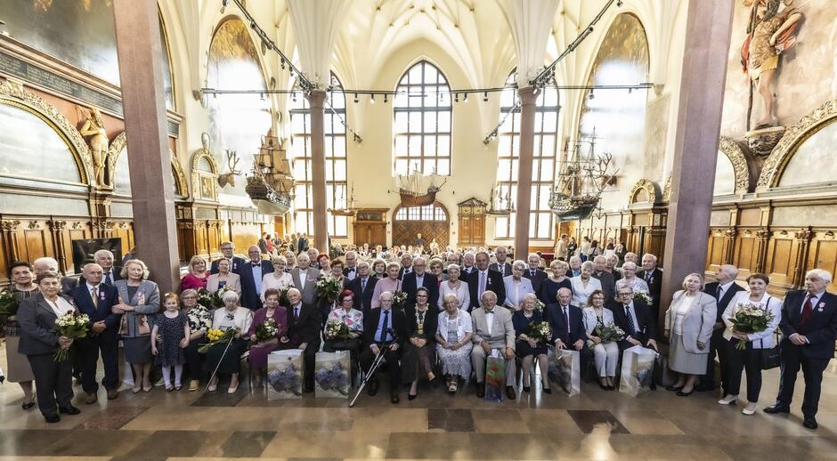 zdjęcie grupowe, pozuje ponad trzydzieści starszych małżeństw, w pierwszy rzędzie osoby siedzą na krzesłach, za nimi już kolejni stoją