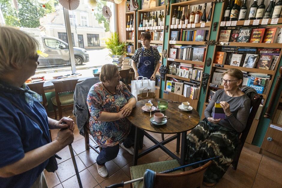 cztery kobiety w księgarni połączonej z kawiarnią, dwie z nich siedzą przy okrągłym stoliku