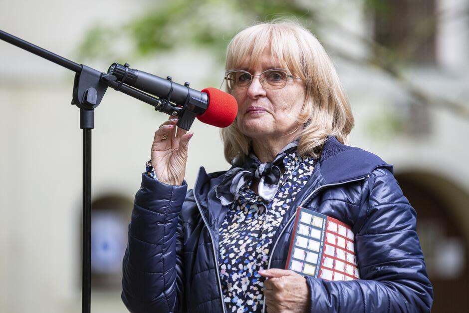 starsza zadbana kobieta w okularach mówi do mikrofonu