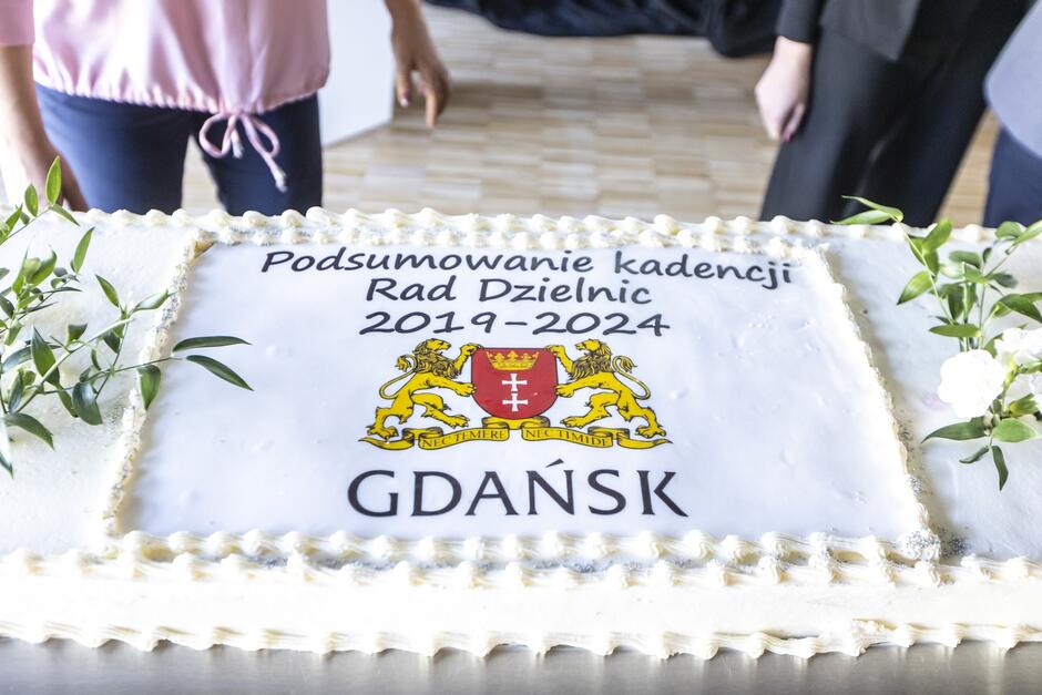 na zdjęciu wielki prostokątny biały tort z napisem podsumowanie kadencji rad dzielnic