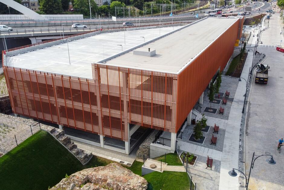 zdjęcie z drona, widać budynek parkingu kubaturowego, ma cztery kondygnacje i elewację wykonaną z brązowo rdzawych podłużnych elementów