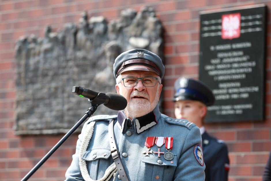Przemawia mężczyzna o siwej brodzie, ubrany w mundur, jaki nosił Józef Piłsudski