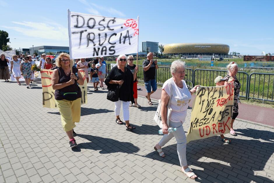 Ludzie z transparentami maszerują w marszu protestacyjnym.