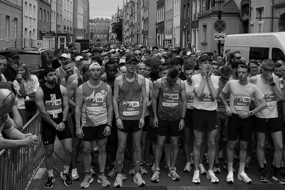 Mężczyźni biegacze stoją na starcie biegu na ulicy miasta