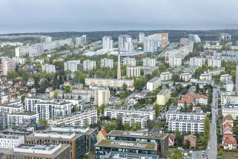 Widok na centrum dużego miasta, wieżowce, kopuły kościołów i stare kamiennice, między nimi drzewa