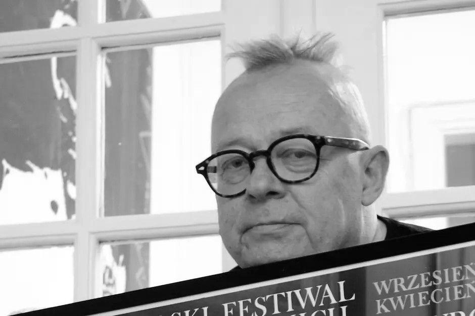 Czarno-białe zdjęcie. Twarz mężczyzny w okularach z nastroszoną kępą włosów na głowie 