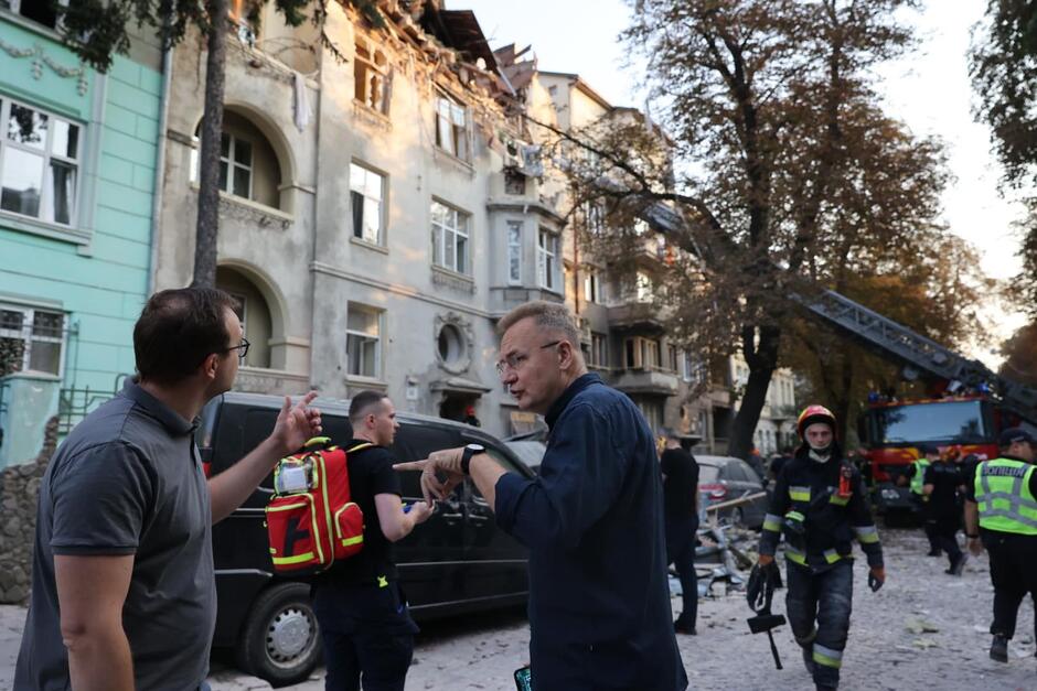 Mer Lwowa pośród strażaków. W tle zniszczona kamienica