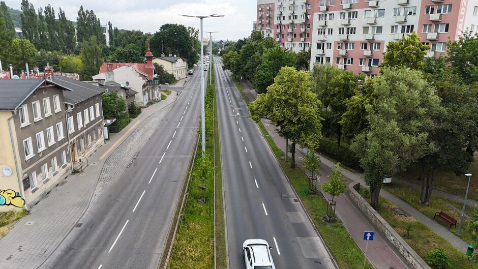 zdjęcie z drona, widać jezdnię dwupasmową w dwóch kierunkach, za jezdnią po obu stronach wysokie bloki mieszkalne