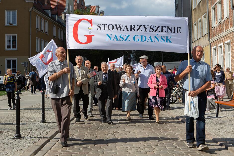 Zdjęcie przedstawia grupę osób maszerujących z transparentem Stowarzyszenie Nasz Gdańsk 