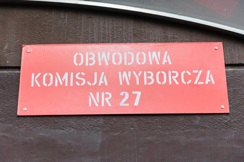 na zdjęciu czerwona tablica z białym napisem obwodowa komisja wyborcza