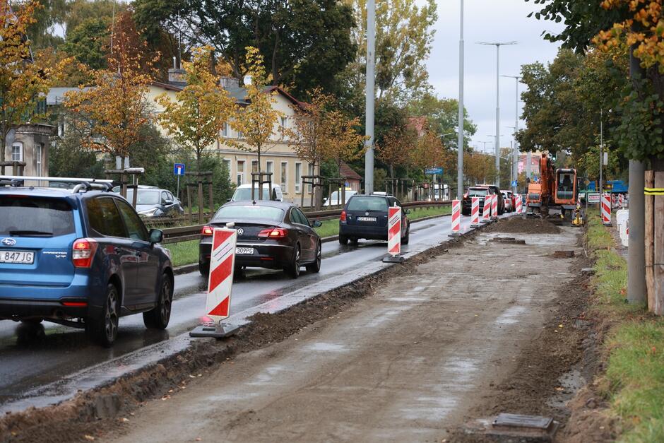 na zdjęciu po prawej widać rozebraną jezdnię na jednym pasie, na drugim pasie jadą jeden za drugim samochody osobowe