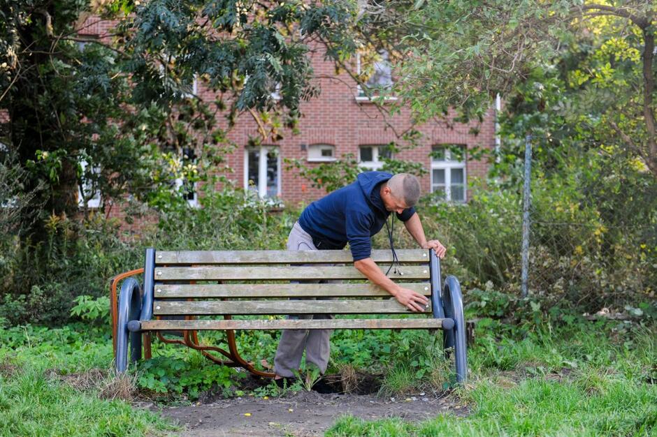 Mężczyzna czyszczący ławkę na podwórku