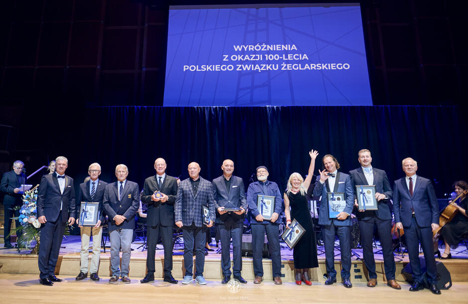 Kilkanaście osób stoi na scenie, w dłoniach mają dyplomy