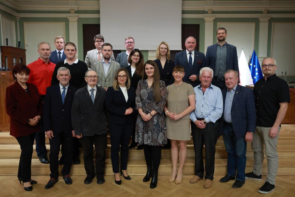 na zdjęciu pozuje około dwudziestu osób, stoją w trzech rzędach na schodkach, wszyscy w odświętnych strojach 