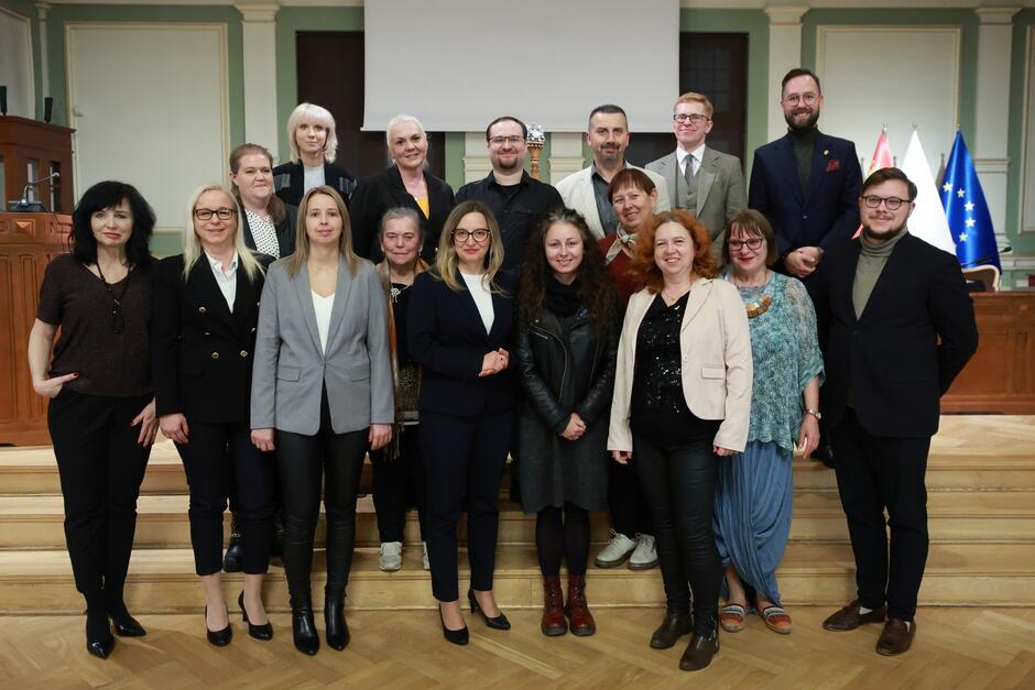 na zdjęciu pozuje około dwudziestu osób, stoją w trzech rzędach na schodkach, wszyscy w odświętnych strojach 