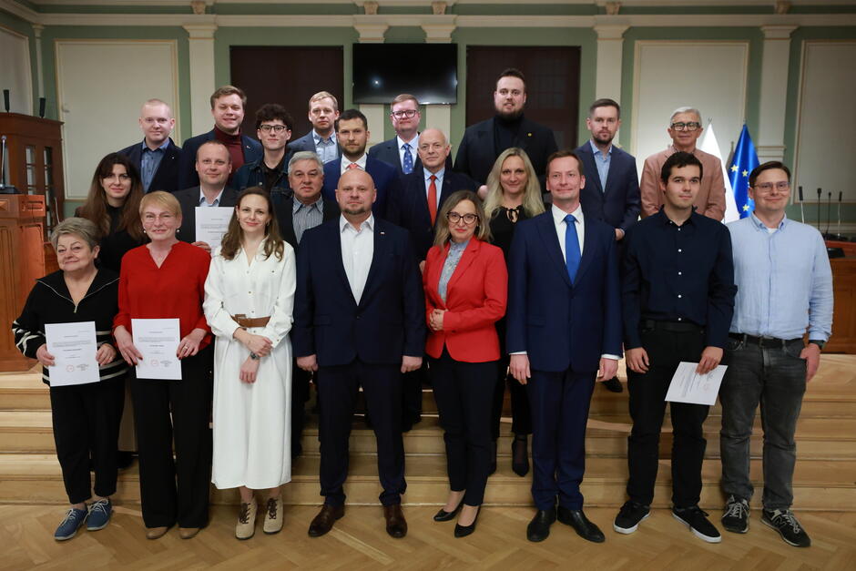 na zdjęciu grupa około dwudziestu osób, pozują do zdjęcia stojąc na schodach w dwóch rzędach