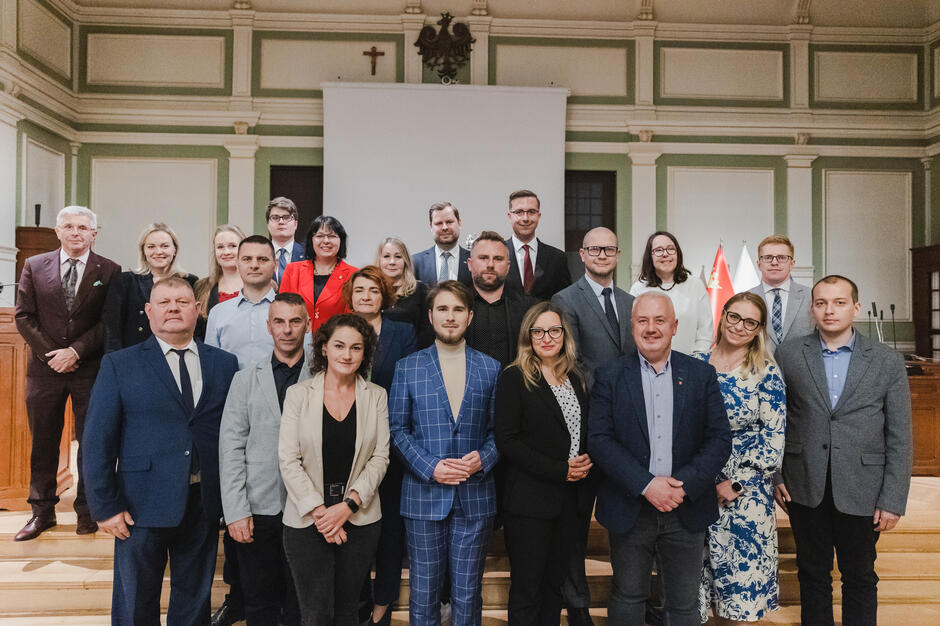 na zdjęciu grupa ponad dwudziestu osób, pozują do zdjęcia stojąc na schodach w trzech rzędach