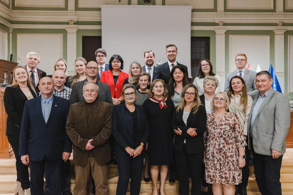 na zdjęciu grupa ponad dwudziestu osób, pozują do zdjęcia stojąc na schodach w trzech rzędach