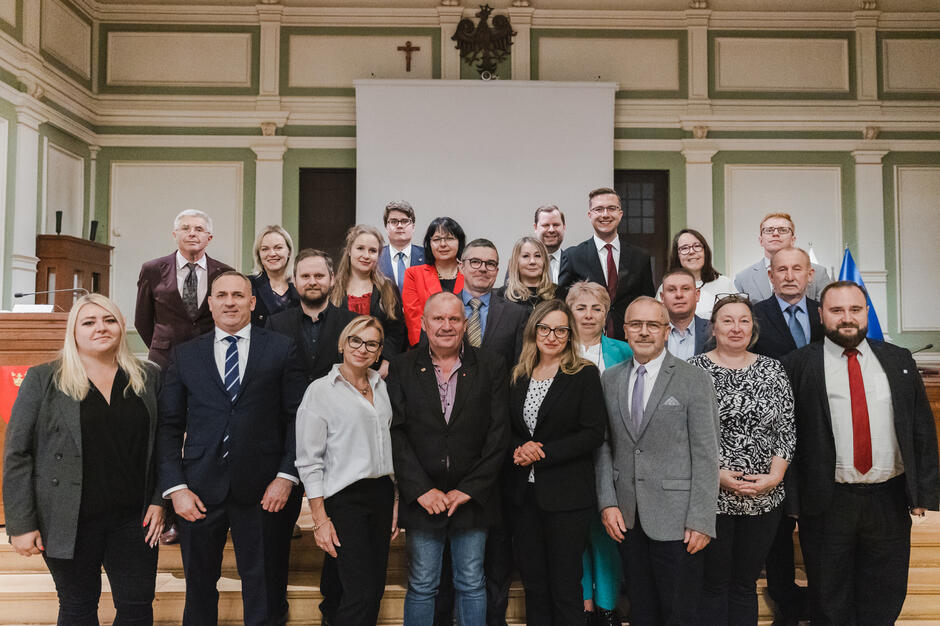 na zdjęciu grupa ponad dwudziestu osób, pozują do zdjęcia stojąc na schodach w trzech rzędach