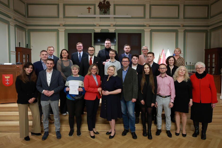 ponad dwadzieścia osób, stojących w dwóch rzędach, pozuje do zdjęcia