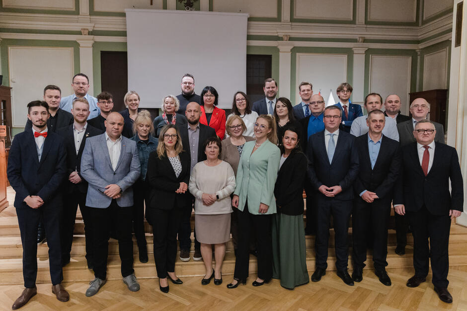 ponad trzydzieści osób stoi w trzech rzędach, pozują do zdjęcia