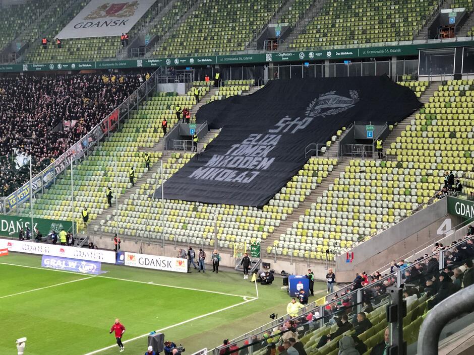 Trybuny stadionu, na nich czarna sektorówka w kształcie koszulki z ich imionami: Eliza, Tomek, Nikodem, Mikołaj