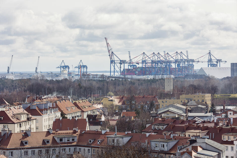 widok na port, dymiący komin, dźwigi portowe, dachy starych domów