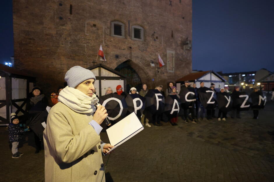 Kobieta przemawia do mikrofonu wieczorem na ulicy miasta.