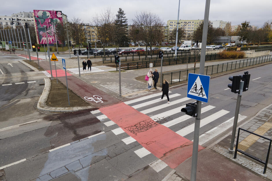 Przejście dla pieszych prowadzi przez kilka jezdni. Obok znak: przejście dla pieszych