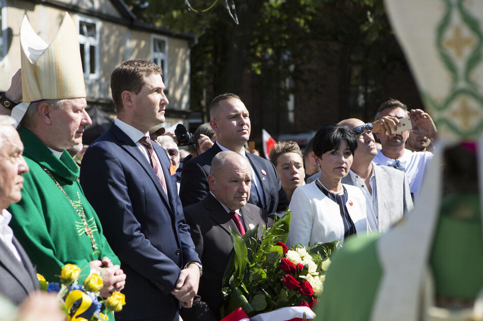 Grupa osób, stoją w milczeniu podczas uroczystości