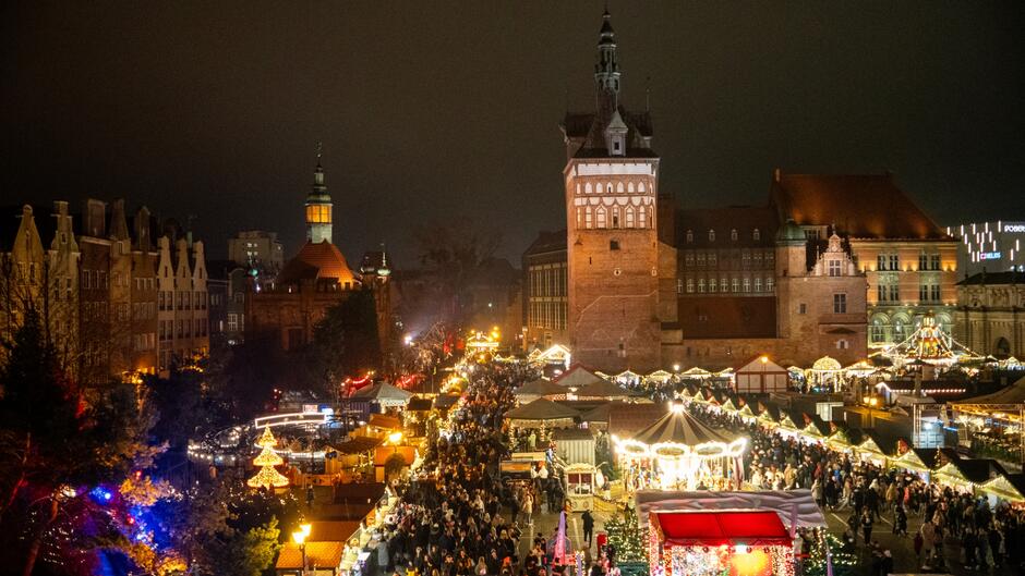 Panorama z tarasu na plac miejski, na którym ustawiono stoiska rozświetlone lampkami