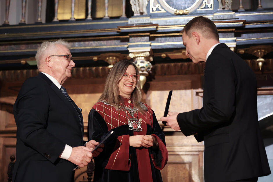 Kobieta i mężczyzna gratulują i wręczają medal mężczyźnie. 